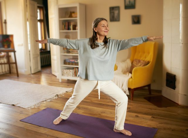 mujer madura haciendo ejercicios de yoga en casa, demuestra los peores ejercicios de pérdida de peso